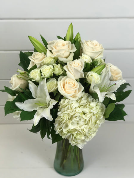 White flowers create a sense of calm with roses, lilies, and hydrangea in a vase