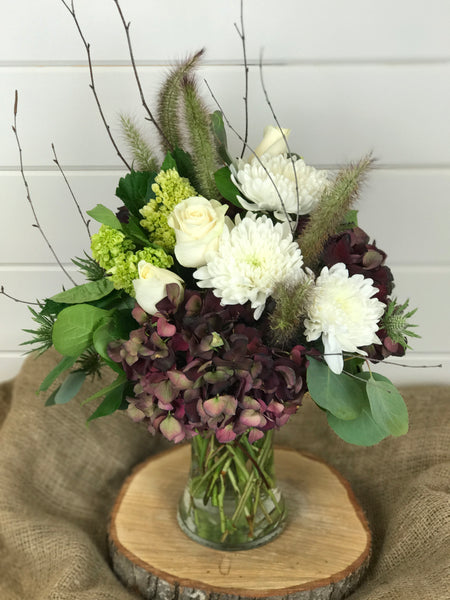 A floral arrangement in a vase of flowers that include hydrangea, mums, roses, for a fall look from a local flower shop in Belmar, New Jersey Gig Morris Florist