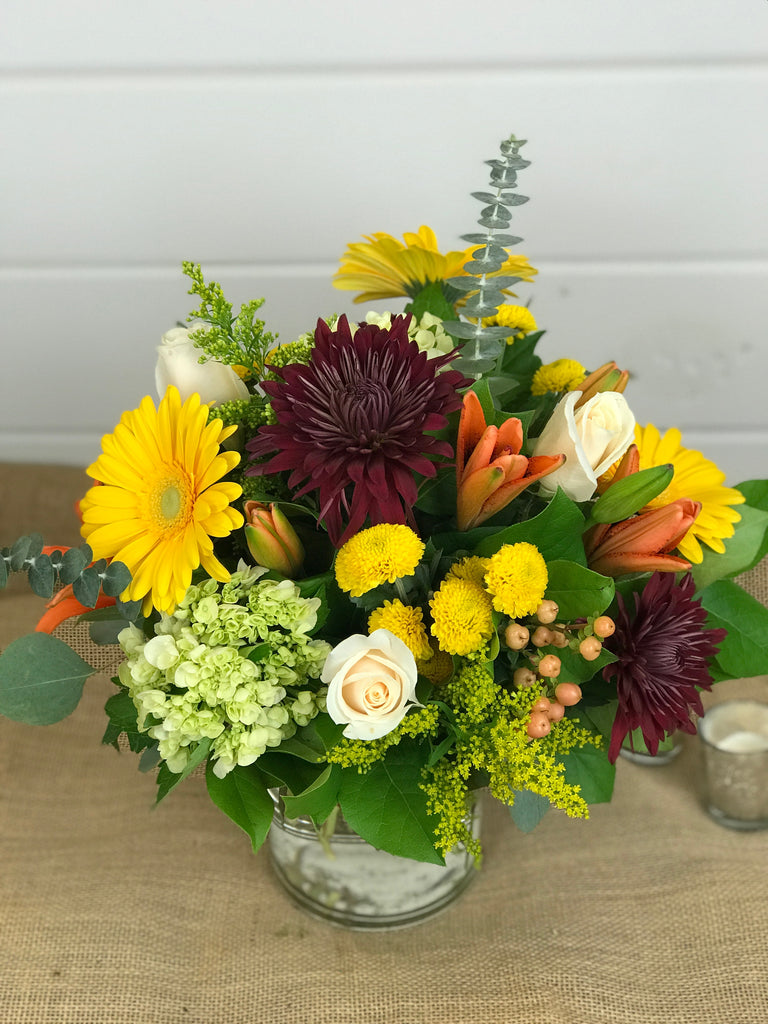 Thanksgiving Day flowers done by Gig Morris Florist in Belmar, New Jersey traditional Thanksgiving centerpiece; a modern cylinder glass vase overflowing with Fall flowers such as lilies, gerber daisies, hydrangea, mums, roses and eucalyptus